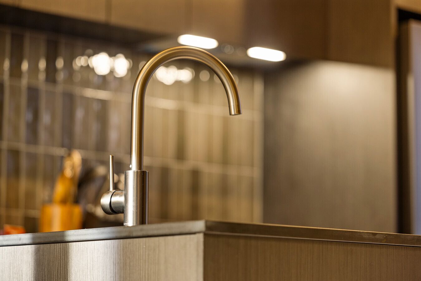 A modern kitchen with a stainless steel sink and faucet.