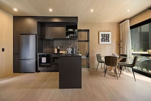 A modern kitchen with a built-in island, dark cabinetry, and a dining area with a glass table and chairs.