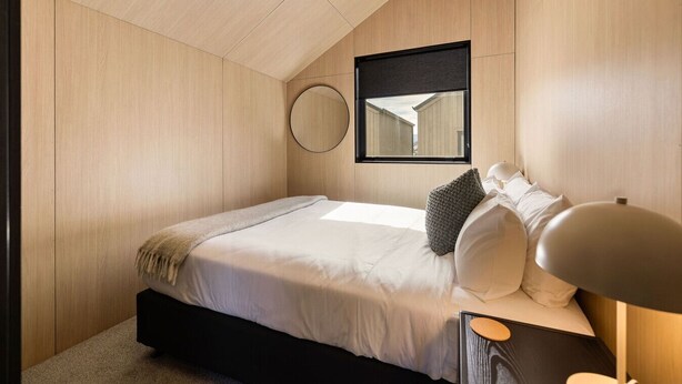 Una camera da letto con un letto, uno specchio rotondo e una lampada da comodino.