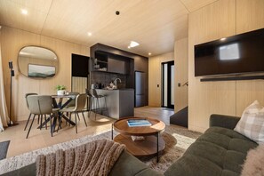 A modern living room with a sofa, a coffee table, and a dining area with chairs. - Rākau Villa Queenstown (Queenstown)