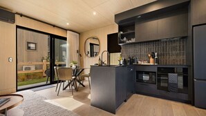 Una cucina moderna con isola centrale, mobili scuri e zona pranzo con tavolo e sedie rotonde.