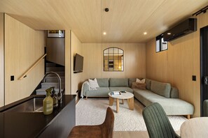 A modern living room with a sofa, coffee table, and a TV mounted on the wall.