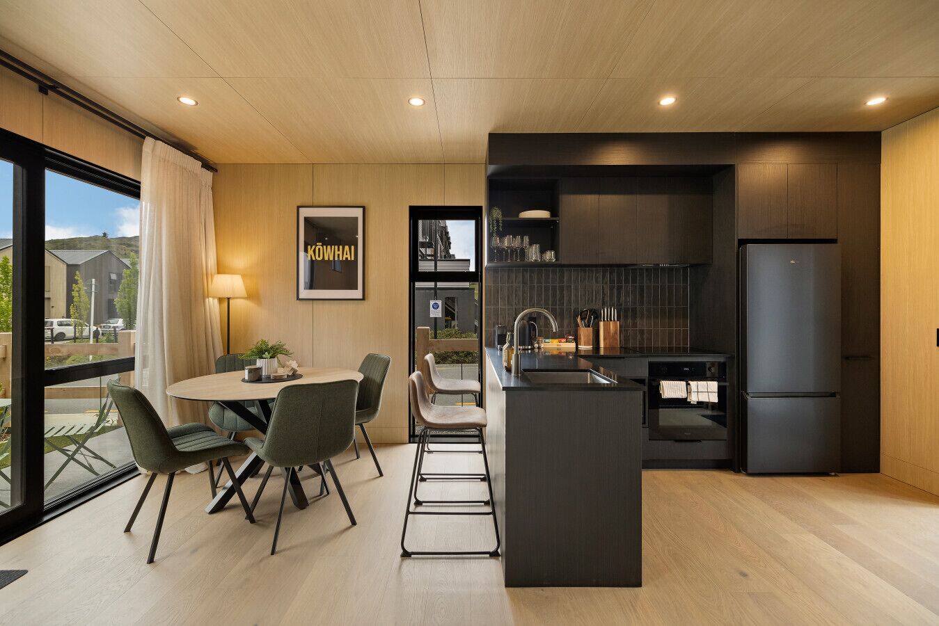Een moderne keuken met een centraal eiland, een eethoek met stoelen en uitzicht op buiten.
