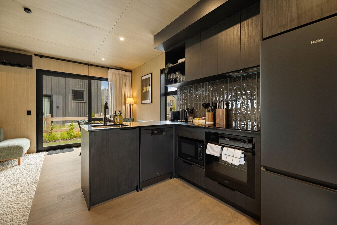 A modern kitchen with dark cabinetry, a central island, and a built-in oven.