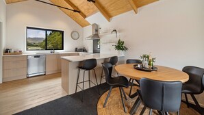 A modern kitchen with a wooden ceiling, a large window, and a dining area with a round table and chairs. - Prime Location, Walk to town, Queenstown (Queenstown)