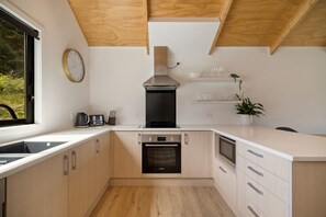 Eine moderne Küche mit Holzschränken, einem Einbauofen, einer Mikrowelle und einer Kaffeemaschine.