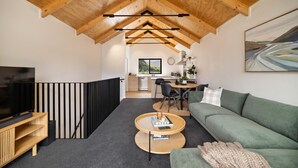 A modern interior with a loft-style ceiling, a green sofa, a coffee table, and a TV on a wooden stand. - Prime Location, Walk to town, Queenstown (Queenstown)