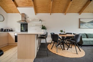 A modern kitchen with a central island, dining area with chairs, and a sofa. - Prime Location, Walk to town, Queenstown (Queenstown)