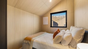 Ein Schlafzimmer mit einem Bett, einem Fenster mit Bergblick und einem gerahmten Bild an der Wand.