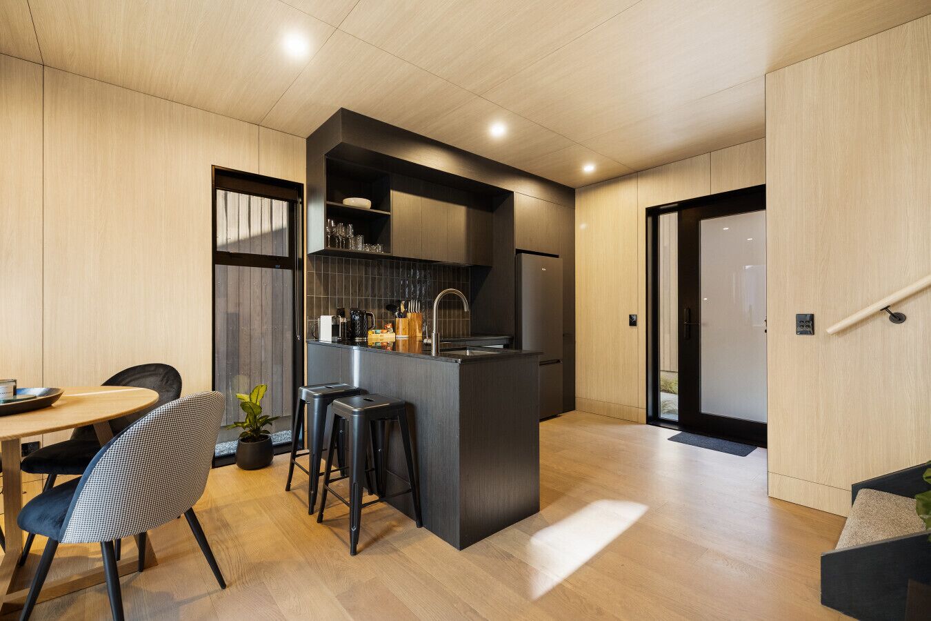 A modern kitchen with a central island, bar stools, and a dining area with a table and chairs.
