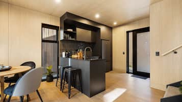 A modern kitchen with a central island, bar stools, and a dining area with a table and chairs.