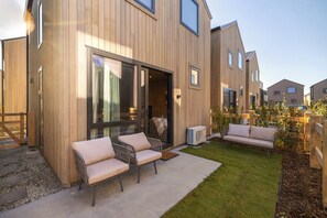A modern wooden building with a patio area featuring outdoor seating and a small garden. - Kawarau Villa, Queenstown (Queenstown)