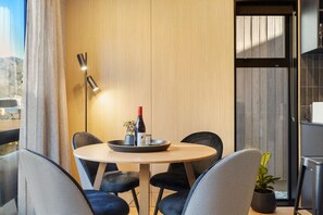 A modern dining area with a round table, black upholstered chairs, a wine bottle, and a small potted plant.
