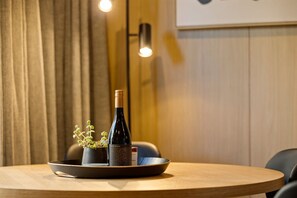 A round wooden table with a wine bottle, a small potted plant, and a bowl on a tray. - Kawarau Villa, Queenstown (Queenstown)