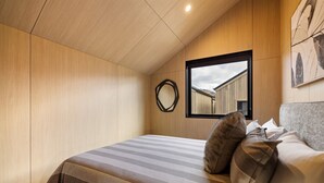 Ein Schlafzimmer mit Bett, einer Katze und einem Fenster mit Blick auf Gebäude.