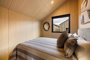 Ein Schlafzimmer mit Bett, einer Katze und einem Fenster mit Blick auf Gebäude.