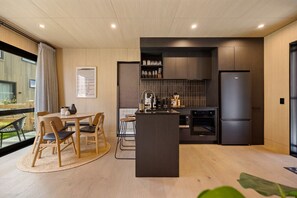 Eine moderne Küche mit einer zentralen Kochinsel, dunklen Schränken und einem eingebauten Backofen.