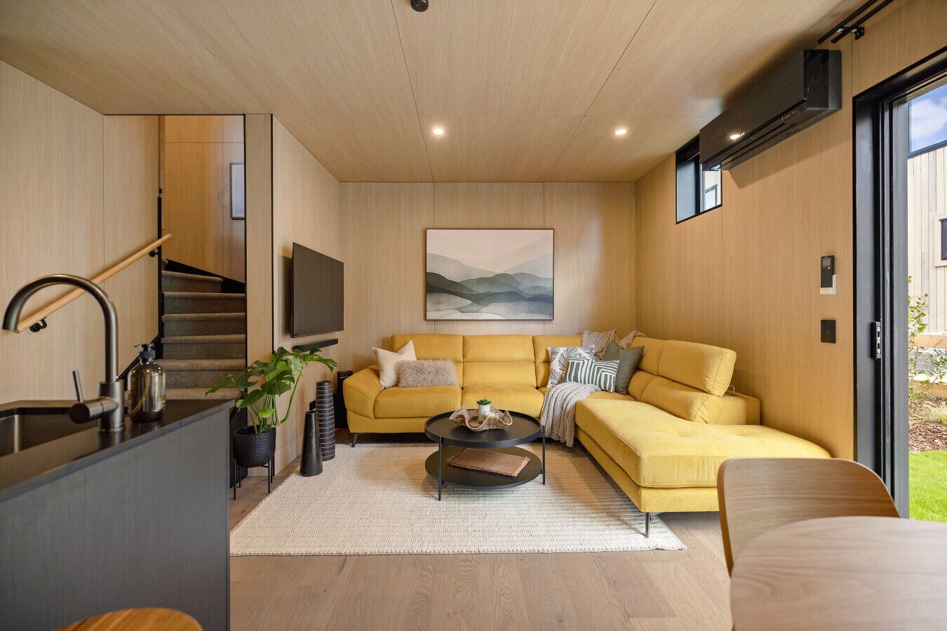 A modern living room with a sofa, coffee table, and a TV mounted on the wall.