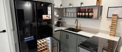 A modern kitchen with grey cabinets, a black refrigerator, a built-in stove, and a sink.