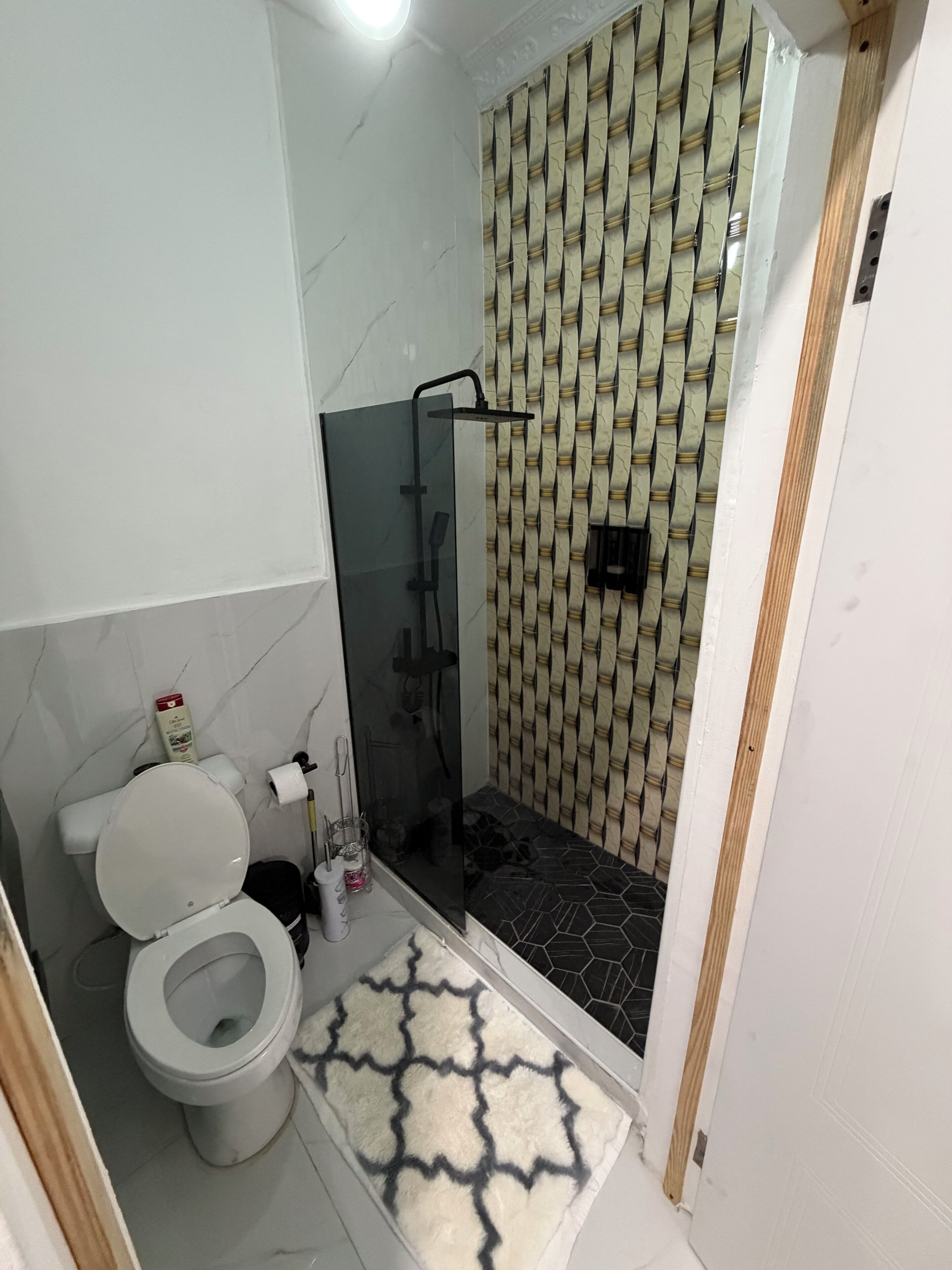Een badkamer met een toilet, een douchecabine en een behang met patroon.