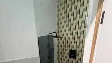Een badkamer met een toilet, een douchecabine en een behang met patroon.