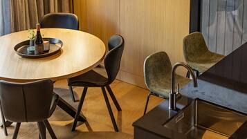 Un espace repas moderne avec une table ronde en bois, des chaises noires et une petite plante en pot.