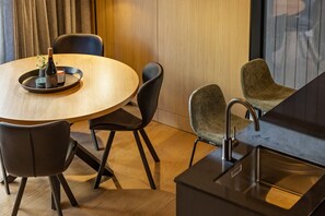 A modern dining area with a round wooden table, black chairs, and a small potted plant. - Te Awa River Retreat w Private Parking (Queenstown)