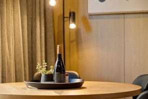 Een ronde houten tafel met een wijnfles, een kleine bloempot en een schaal op een dienblad.