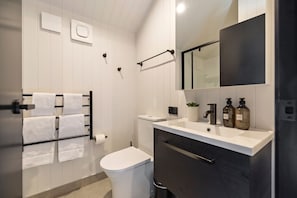 Een moderne badkamer met toilet, wastafel en handdoekhouder.