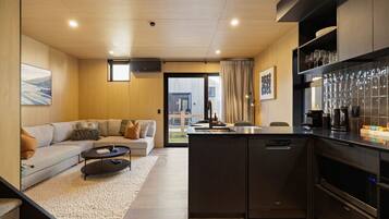 A modern kitchen with dark cabinetry, a built-in dishwasher, and a coffee maker.