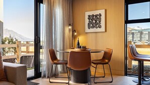 Un espace de salle à manger moderne, avec une table ronde, des fauteuils en cuir et une vue sur les montagnes grâce à de grandes fenêtres.