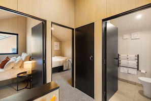 Hotelkamer met een bed, nachtkastje, lamp en uitzicht op de stad door een raam.