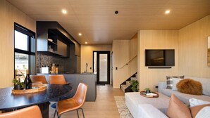 Une cuisine moderne avec un coin repas, un escalier et un salon doté d’un canapé et d’une télévision.