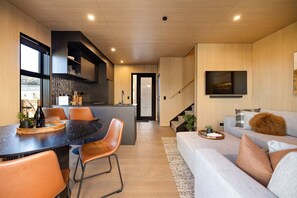 Une cuisine moderne avec un coin repas, un escalier et un salon doté d’un canapé et d’une télévision.