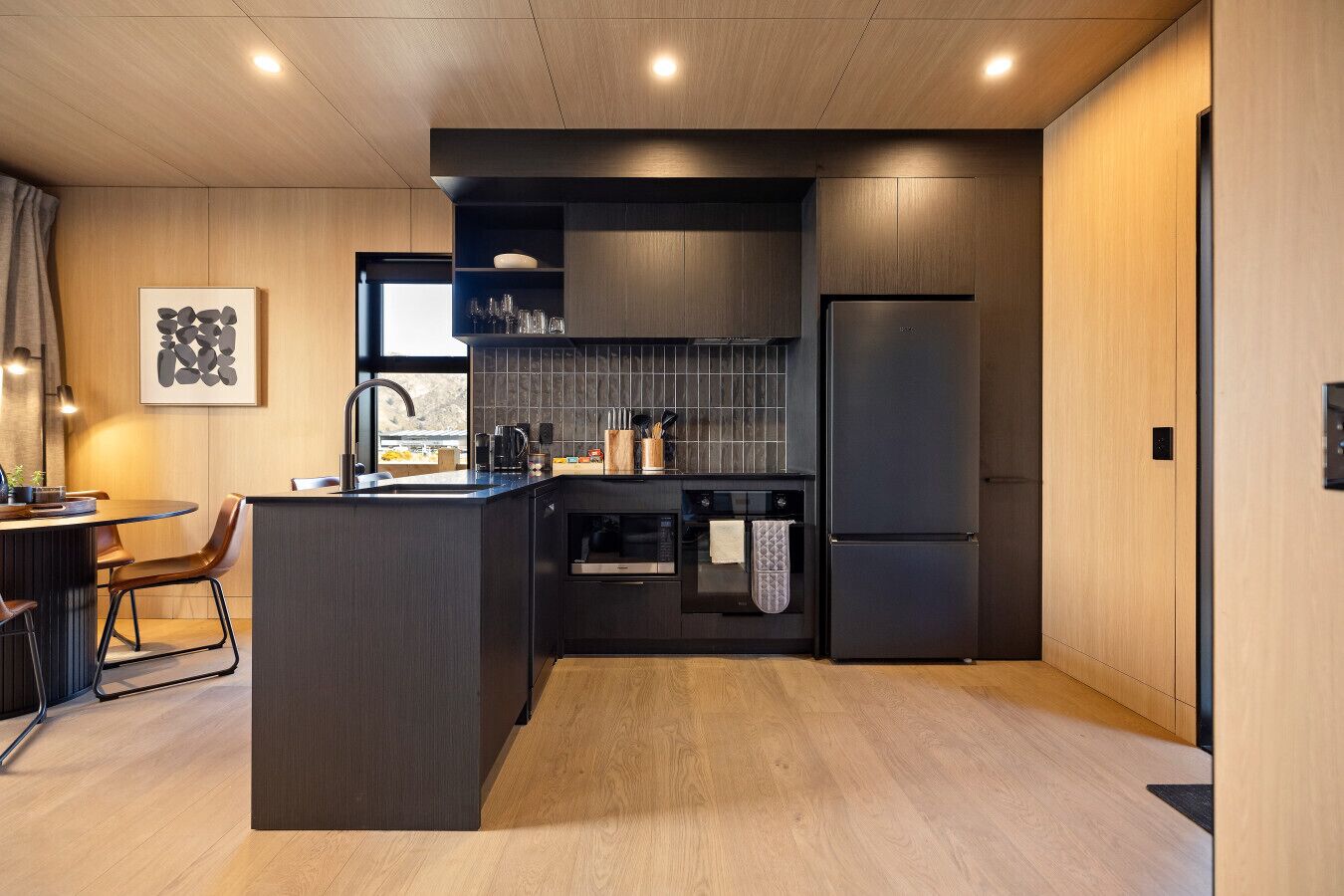 Cozinha moderna com ilha central, forno embutido e uma geladeira grande.