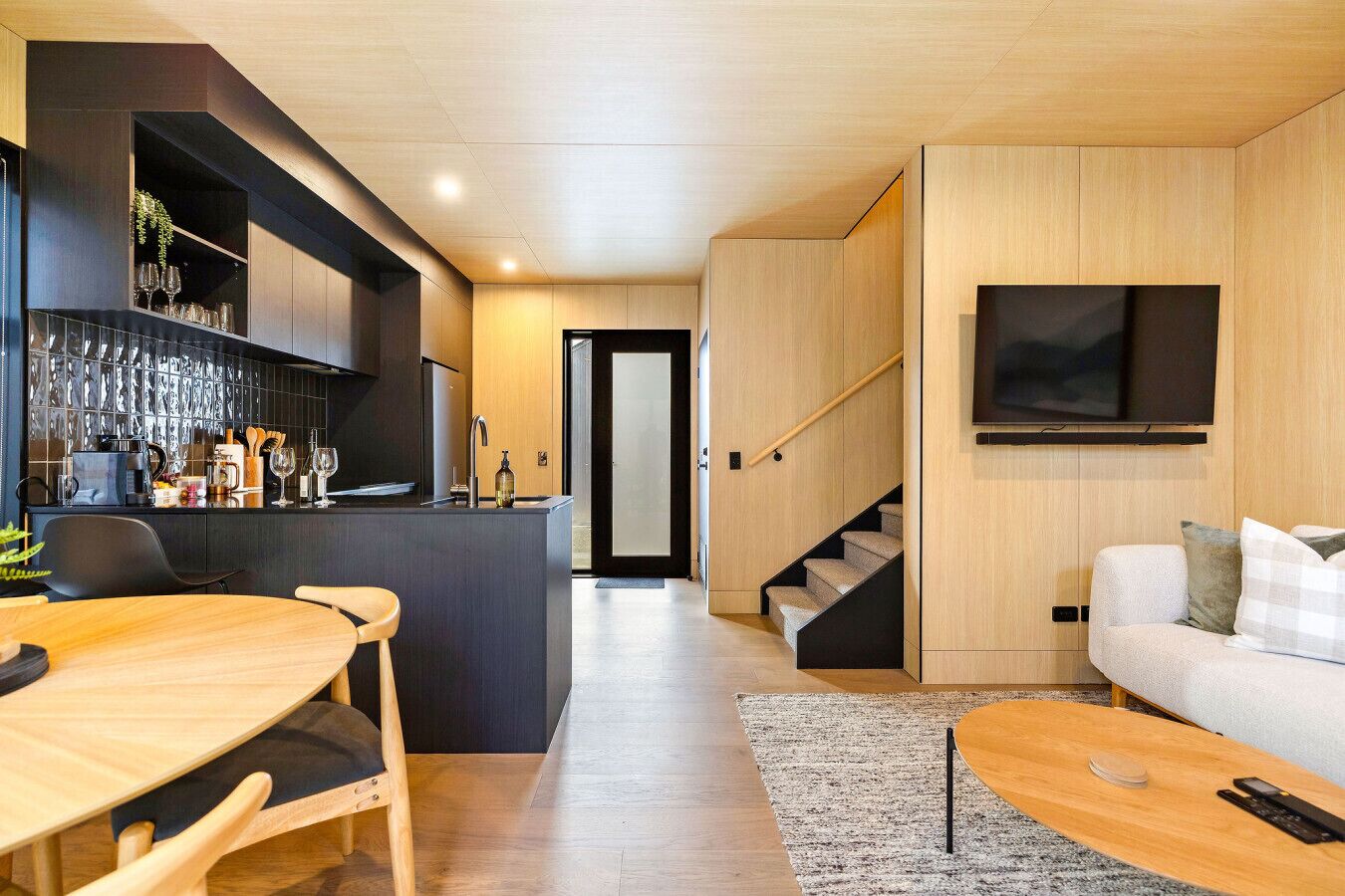 Um espaço de estar moderno com cozinha, sala de jantar e escada para outro nível.