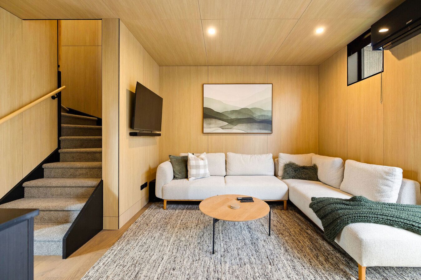 Uma sala de estar moderna com um sofá, uma mesa de centro e uma escada.