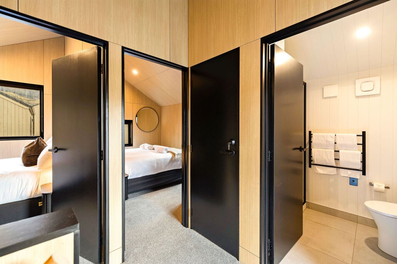 Une chambre d’hôtel avec un lit, un miroir rond et une salle de bain équipée de toilettes et d’un porte-serviettes.