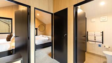 Une chambre d’hôtel avec un lit, un miroir rond et une salle de bain équipée de toilettes et d’un porte-serviettes.