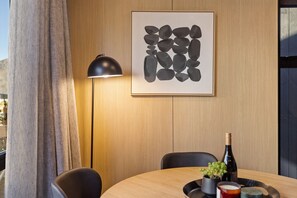 A modern dining area with a wooden table, black chairs, a floor lamp, and a framed abstract art piece on the wall. - Rāua Luxury Villa, Queenstown (Queenstown)
