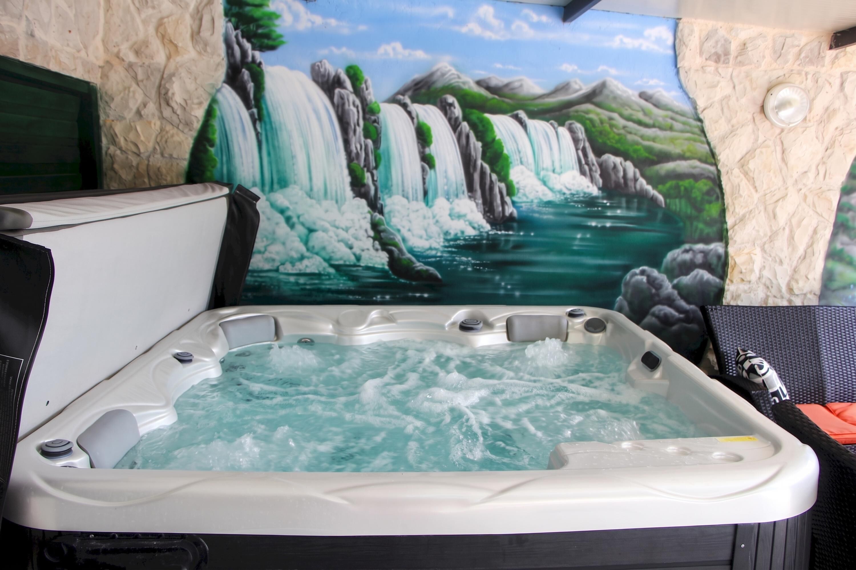 A hot tub with a waterfall mural in the background.