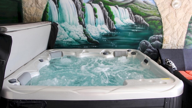 Een bubbelbad met een wanddecoratie van een waterval op de achtergrond.