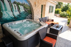 Ein Whirlpool mit Wandgemälde eines Wasserfalls, Sitzgelegenheiten im Freien und eine Steinwand.