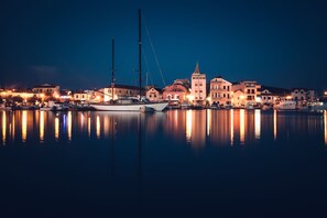 Ein Yachthafen bei Nacht mit vertäuten Booten und Gebäuden entlang der Uferlinie.