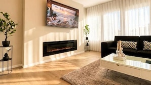 Un salon moderne avec une cheminée, un canapé noir, une table basse et un tableau au mur.