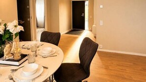 Un coin repas avec une table ronde dressée pour quatre personnes, deux chaises et un vase rempli de fleurs.