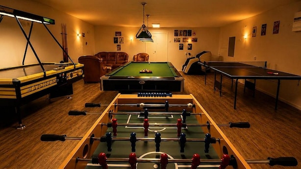 Une pièce équipée d’un baby-foot, d’une table de billard et d’une table de ping-pong.