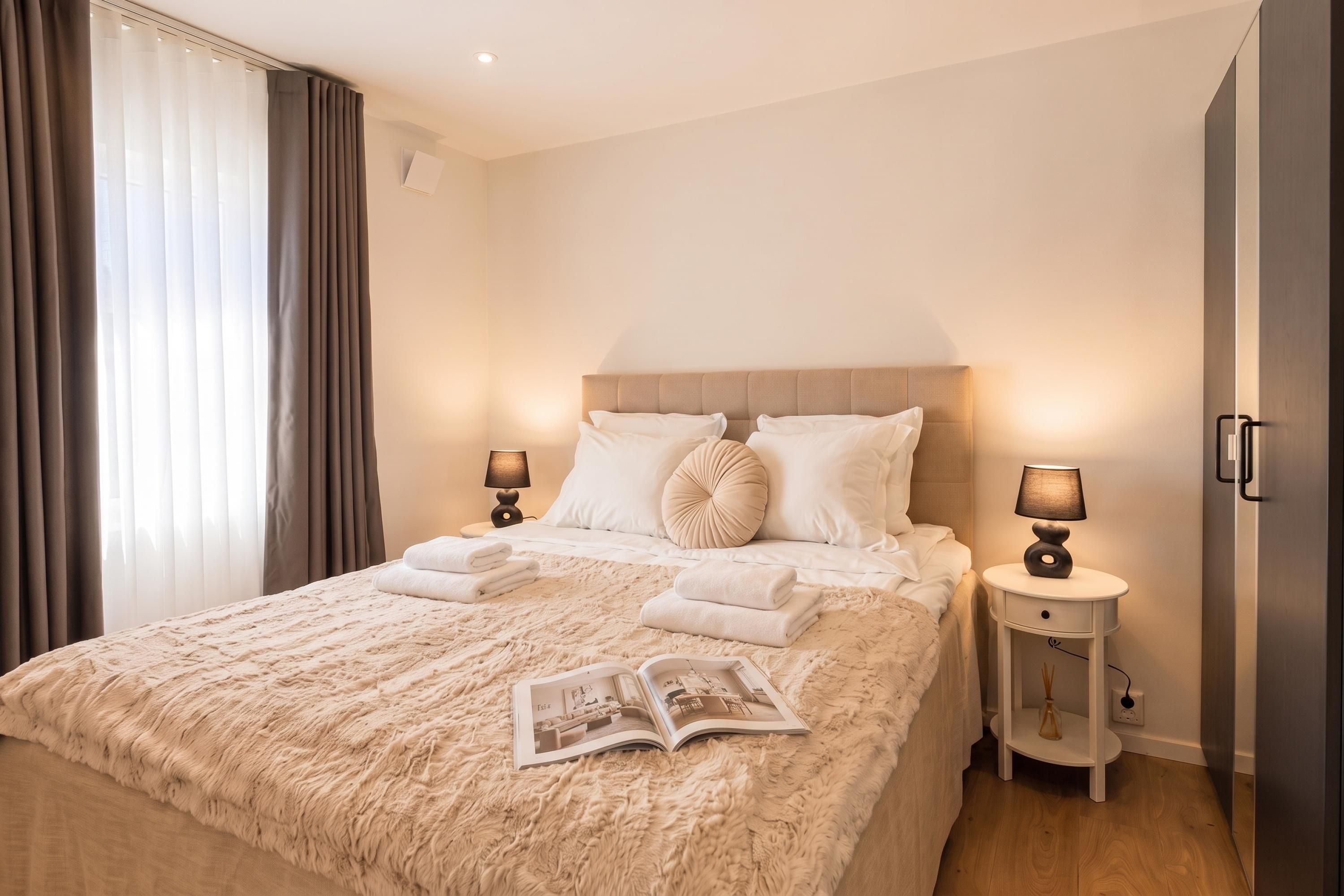 Una habitación de hotel con una cama grande, dos mesitas de noche y un ventanal con cortinas.