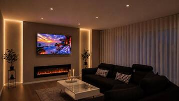 Ein modernes Wohnzimmer mit Flachbildfernseher, Kamin, schwarzem Sofa und Glastisch.