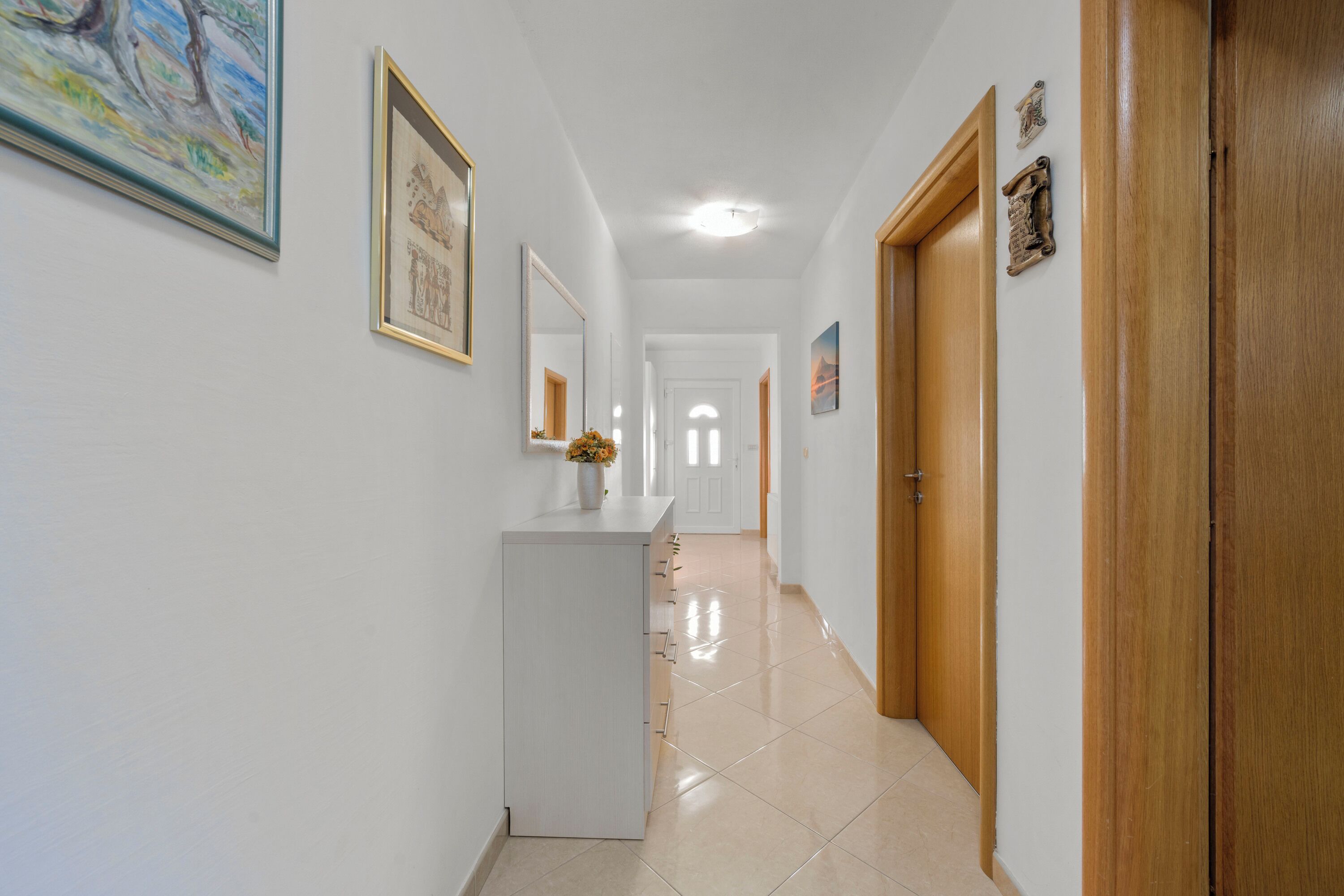 A hallway with a white reception desk, wooden doors, and framed artwork on the walls.